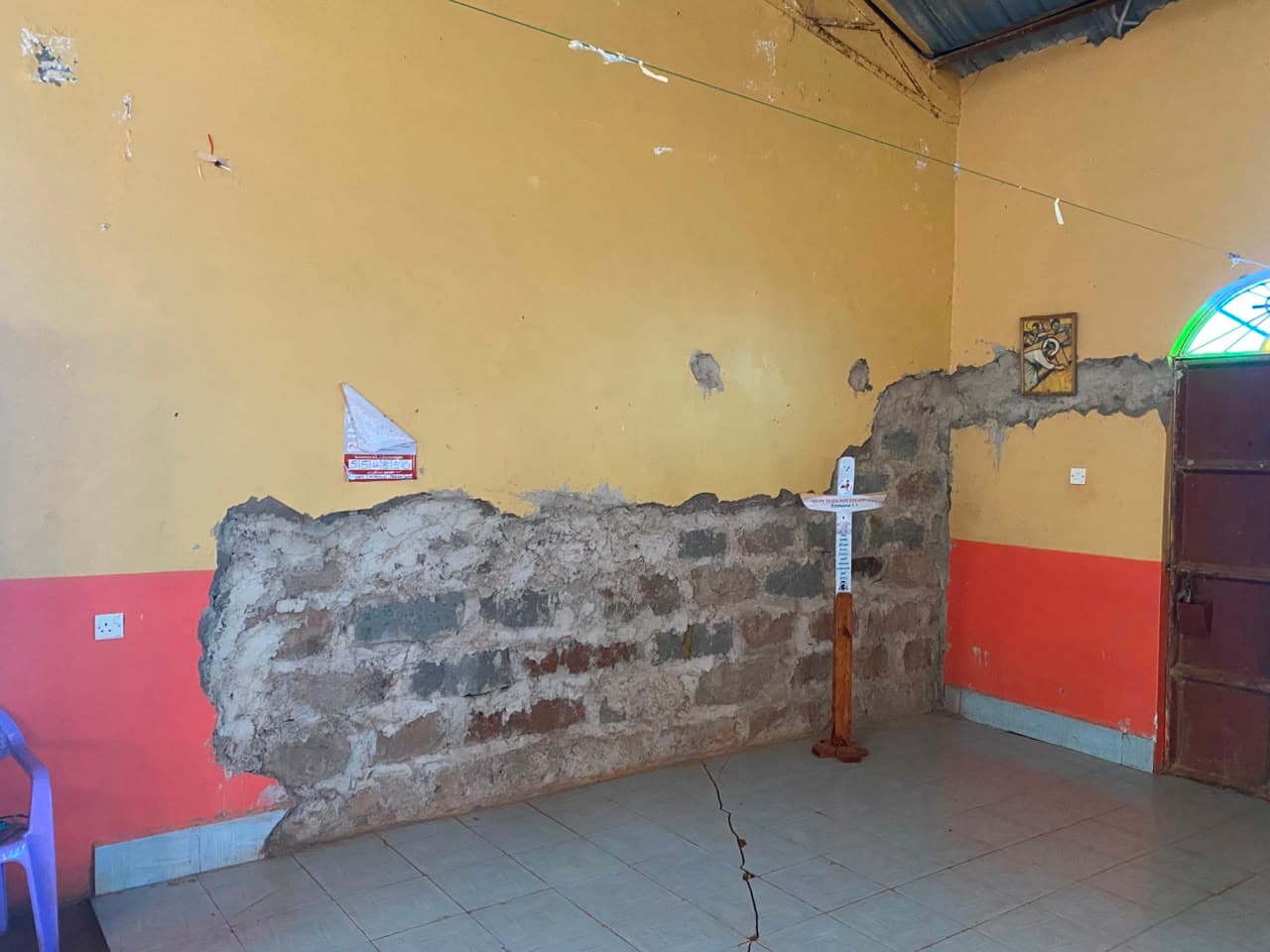 A close view of the unfinished wall and a crack running through the floor tiles.
