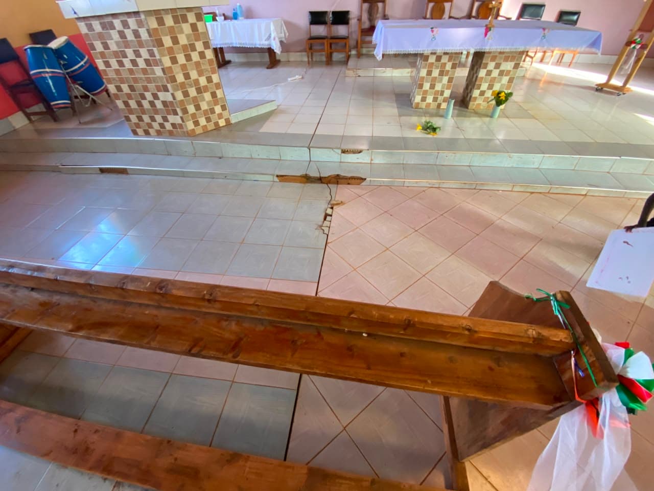 Cracked, sinking floor tiles at the foot of the altar steps.